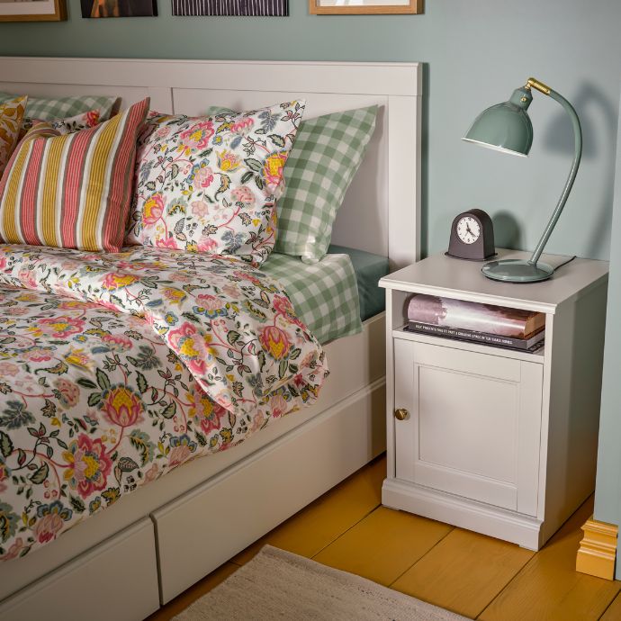 Dormitorio con una mesita de noche FÅGELFJÄLLET y una cama vestida con ropa de cama floral DAGGSALVIA.