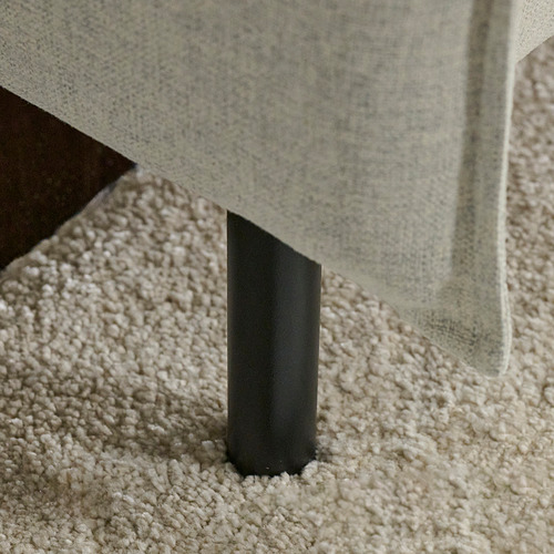 Sofá moderno con patas minimalistas de acero negro, que ofrece comodidad acogedora con cojines mullidos.