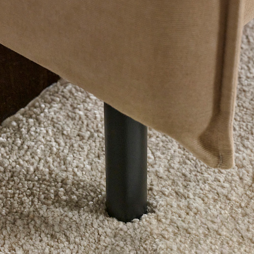 Sofá moderno con patas negras y elegantes sobre una moqueta suave y texturizada. Respaldo alto, acolchado para mayor comodidad.