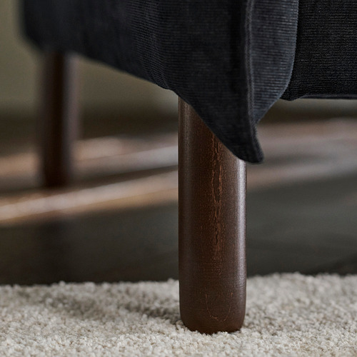 Sofá moderno con respaldo alto, tapicería oscura y patas de madera elegantes.