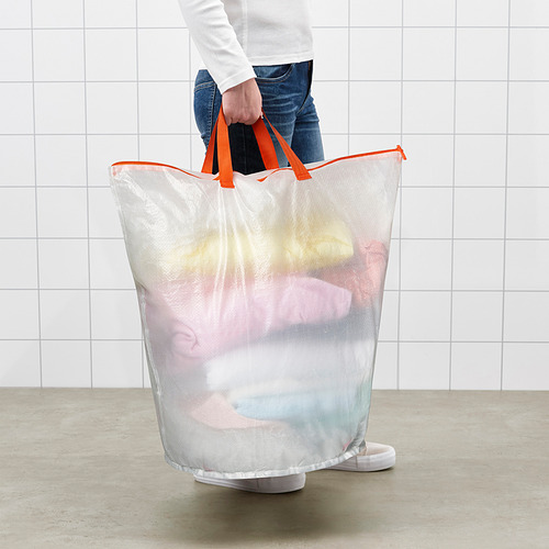 Persona sosteniendo una bolsa de lavandería de malla con asas de color naranja brillante llena de ropa.