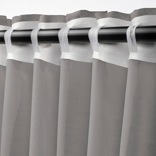 Barra de cortina con cortinas STENFRÖ grises transparentes, plisadas con cinta de cabecera blanca, que difunden la luz del día.