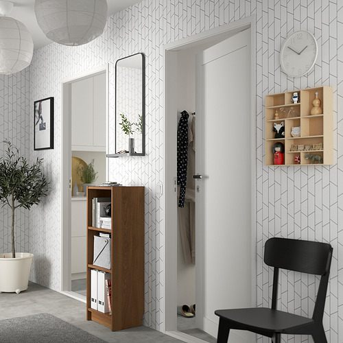 Entrada moderna con estantería BILLY, vegetación, silla y pared geométrica.