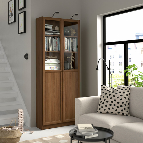 Sala de estar moderna con librería BILLY, sofá blanco, lámpara de pie negra y ventana.
