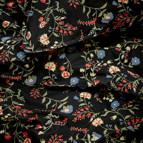 Funda nórdica negra con flores rojas, azules, amarillas, dobladas, patrón intrincado.