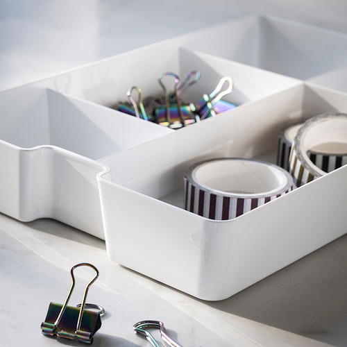 Bandejas organizadoras blancas con suministros de escritorio. Incluye clips de colores y cinta a rayas.