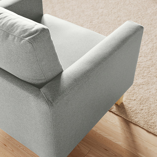 Sillón moderno de tela gris sobre suelo de madera. Diseño cómodo tapizado con detalles en el cojín trasero.