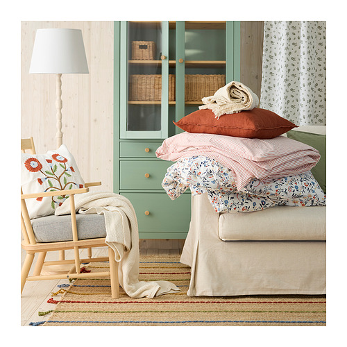 Acogedora sala de estar con alfombra RAKLEV, sillón, armario verde y cama.