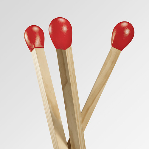 Tres lámparas de pie de madera de gran tamaño en forma de cerillas cruzadas, con puntas rojas.