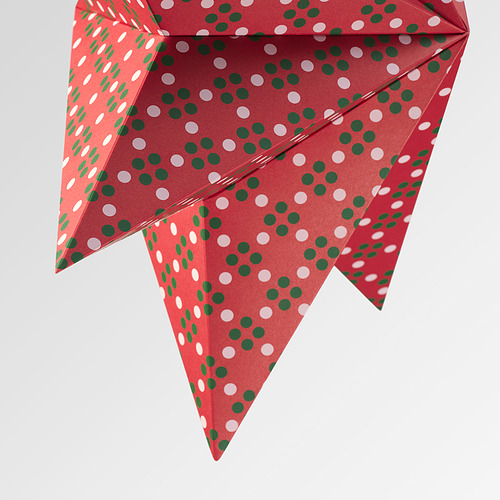 Lámpara de papel rojo con lunares verdes y blancos, doblados en intrincadas formas geométricas.