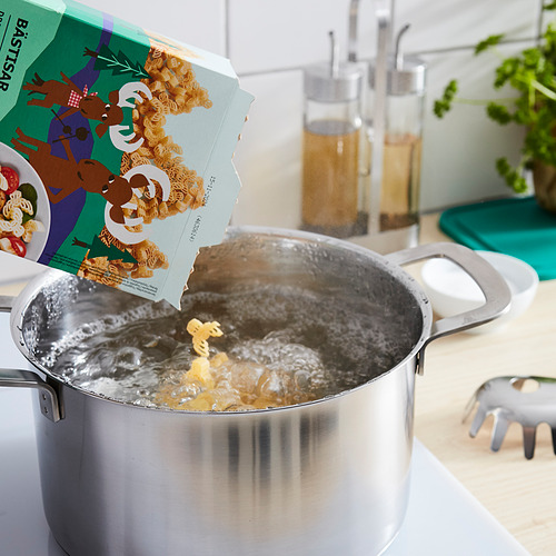 Pasta hirviendo en sartén de plata con empaque BÄSTISAR en forma de alce que se vierte. Fondo de cocina.