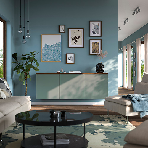 Aparador BESTÅ en salón moderno con paredes azules, plantas y obras de arte.