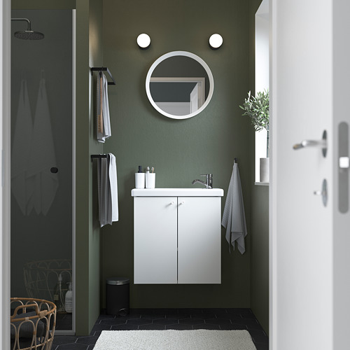 Baño moderno con tocador blanco ENHET , espejo redondo, paredes verde oscuro, suelos negros, toallas blancas y ducha.
