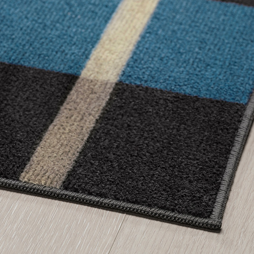Una moderna alfombra de rayas con colores azul, gris y beige colocada sobre un suelo de madera.