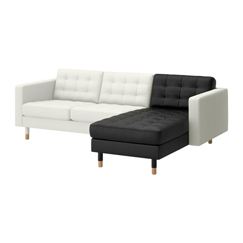 Un sofá de cuero blanco y negro en forma de L con patas de madera.