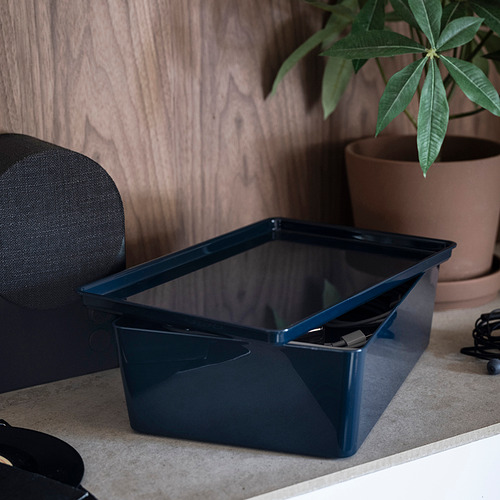 Caja azul de KUGGIS en el escritorio, con tapa, usada para guardar objetos de oficina.