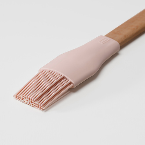 Cepillo de silicona rosa claro con mango de madera, perfecto para tareas de repostería.