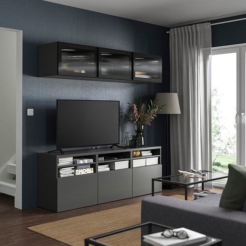 Sala de estar moderna con paredes de color gris oscuro, TV de pantalla plana y centro de entretenimiento de vidrio de caña.