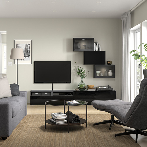 Sala de estar moderna con sofá gris, tv, mesa de centro, libros, estanterías de caña, gran ventanal, cortinas, lámpara de pie.
