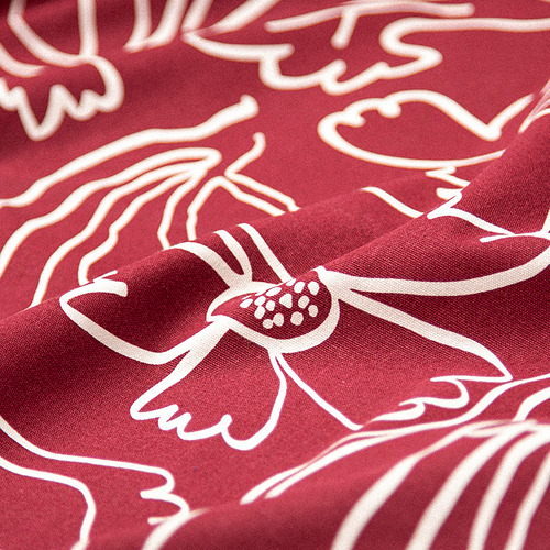 Mantel de algodón rojo reciclado con intrincado patrón floral blanco, que muestra una artesanía de alta calidad y materiales ecológicos.