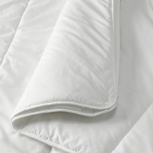 Edredón nórdico blanco doblado sobre la cama, tela suave y lisa, bordes cuidadosamente cosidos.