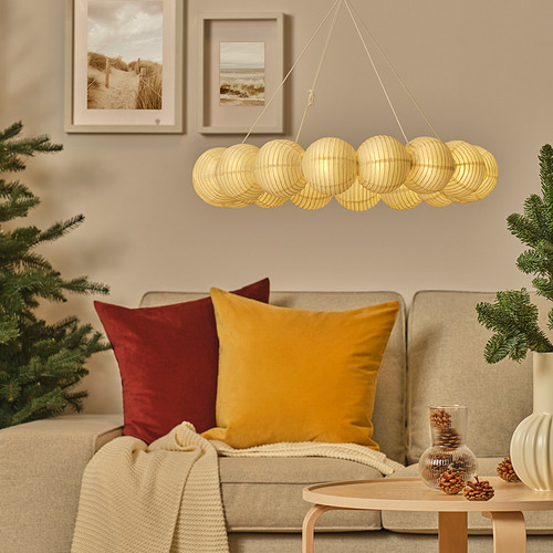 Acogedora sala de estar con sofá beige, almohadas de colores, faroles dorados colgantes y árbol de Navidad decorado.