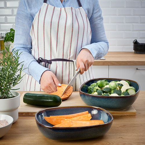 Una persona prepara verduras en una cocina utilizando platos de horno GLADELIG para servir.