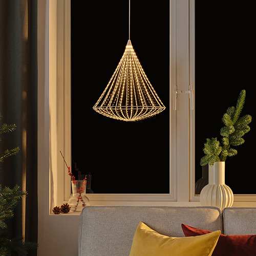 Lámpara STRÅLA sobre sofá gris con almohadas de colores, diseño esférico blanco, cerca de la ventana y el jarrón.