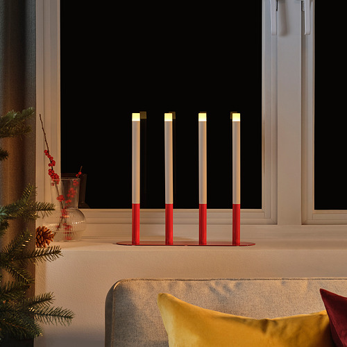 Velas led STRÅLA rojas, diseño moderno, en el alféizar de la ventana junto al sofá.