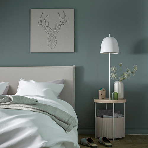 Dormitorio minimalista con mueble TRINDSNÖ. Lámpara blanca, mesa auxiliar, cesta de almacenamiento. Paredes azul verdoso, acentos pastel.