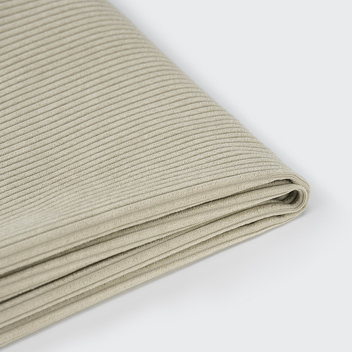 Primer plano de la colcha de cama de color beige claro con textura sutil, cuidadosamente doblada.