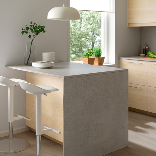 Cocina moderna con isla de madera clara MÖCKLARP, taburetes de bar blancos, lámpara colgante y decoración de encimera.