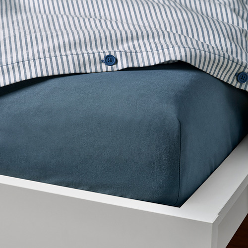 Cama con almohada de rayas azules, sábana azul oscuro y marco blanco.