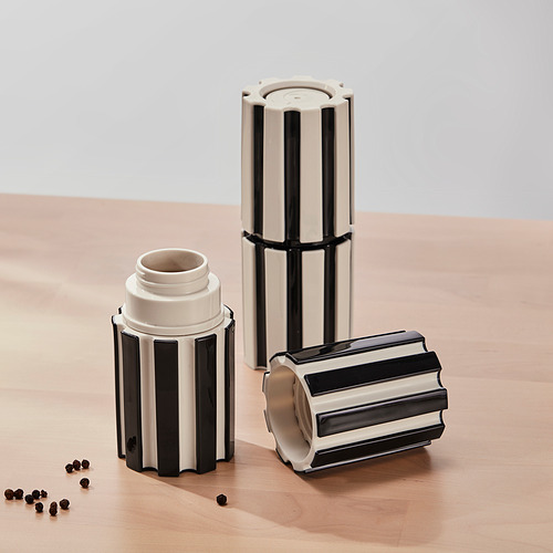 Tres molinos de especias rayados sobre madera, uno abierto con especias dispersas.