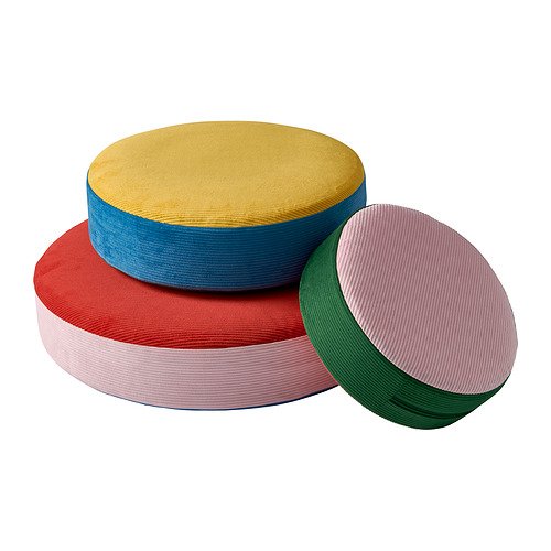 Tres cojines circulares apilados en amarillo, azul y rojo con diseño texturizado y acanalado hecho de poliéster reciclado.