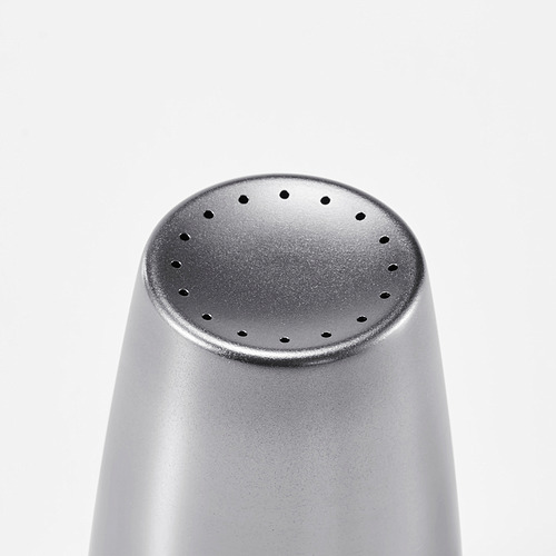 Mira un molinillo de pimienta redondo, metálico. Fíjate en la superficie texturizada y los pequeños agujeros en la parte superior.