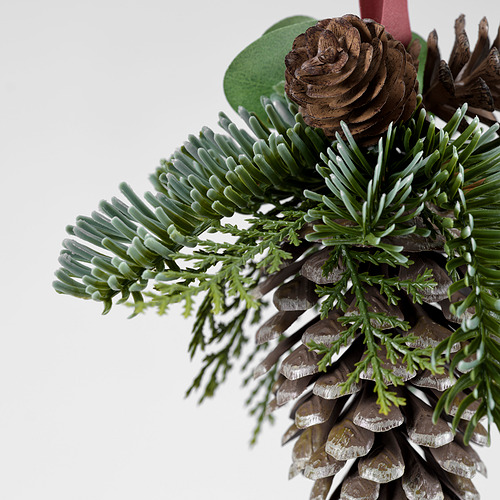 Primer plano de piña festiva y corona de vegetación artificial, bellamente detallado, perfecto para la decoración navideña.