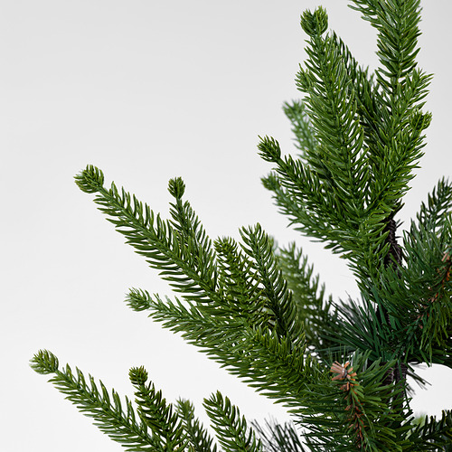 Primer plano de agujas de pino verdes exuberantes y vibrantes en un árbol de Navidad artificial realista, que muestra su calidad y textura realista.