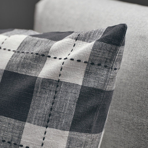Blanco y negro: una funda de cojín a cuadros con costuras negras en un sofá, que muestra su calidad, textura y diseño.