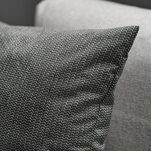 Primer plano de una almohada de tela suave y texturizada sobre un cojín gris, que muestra un tejido intrincado y un brillo sutil.