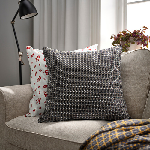 BRUNNYCKLAR cojín gris sobre sofá beige, más grande que la almohada floral roja, manta de cuadros amarillos.