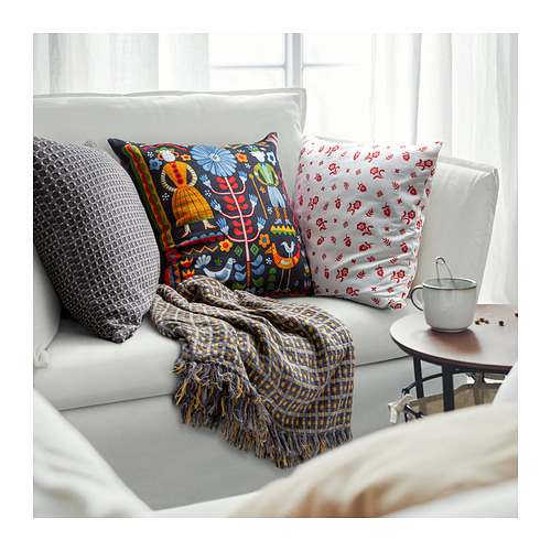 Acogedor sofá con coloridos cojines, manta doblada y taza de café; Mezcla de estampados y texturas.