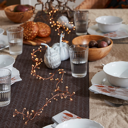 Mesa acogedora con luz STRÅLA, calabazas, cuencos, tazas y vasos, que crean un cálido ambiente otoñal.