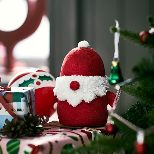 Estatuilla de Papá Noel rojo sentada cerca de regalos. Más pequeño que los regalos.