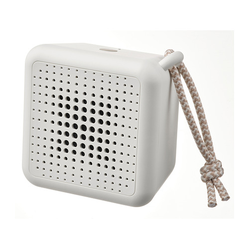 Representa un altavoz VAPPEBY portátil y blanco con una rejilla de pequeños orificios para el sonido y una cuerda trenzada para transportarlo, sobre un fondo blanco.