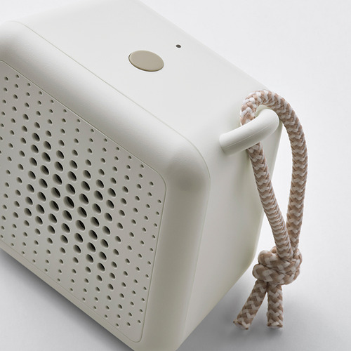 Altavoz compacto y portátil con mango trenzado, acabado liso y numerosos orificios para la salida de audio.