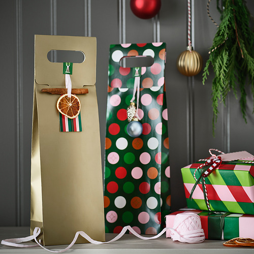Dos bolsas de regalo, dorada con naranja seco y verde con lunares, con cinta a rayas y pequeños regalos, montaje festivo.