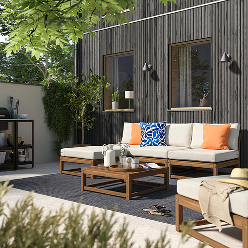 Patio moderno con sofá seccional NÄMMARÖ, mesa de centro, almohadas de colores y plantas.