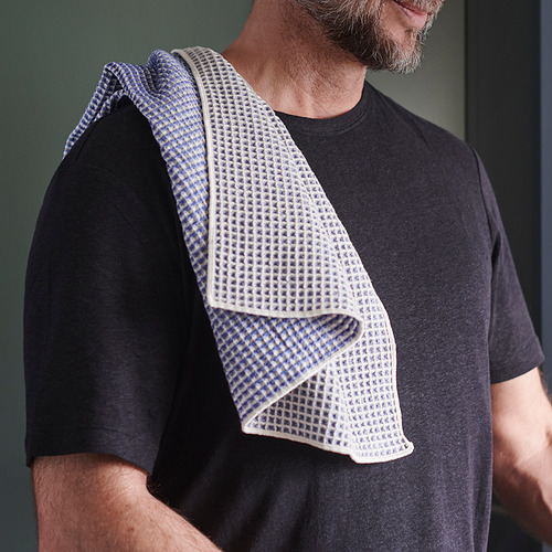Hombre que viste una camisa negra con una tela estampada azul y blanca sobre el hombro.