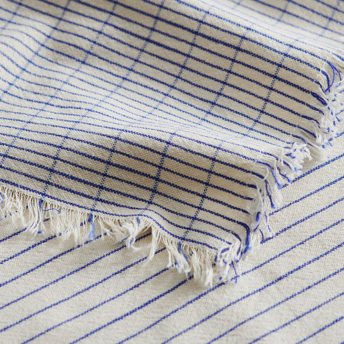Manta de rayas beige y azul con flecos.